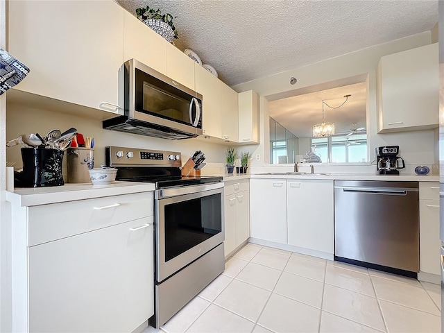 kitchen with sink, appliances with stainless steel finishes, white cabinetry, and a notable chandelier