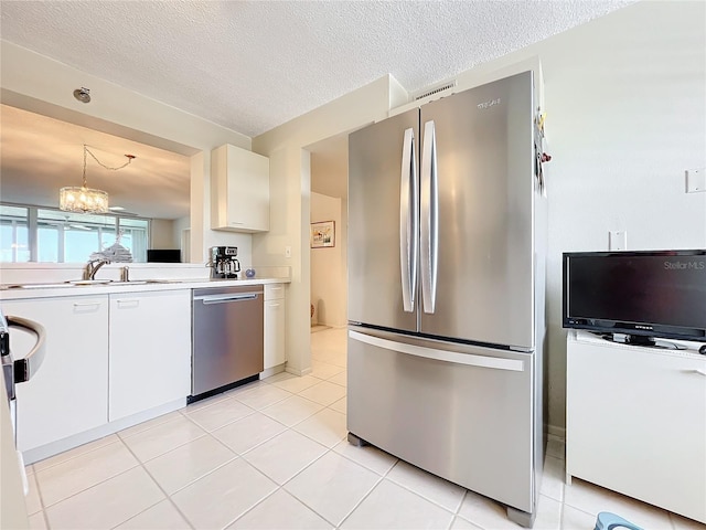 kitchen featuring appliances with stainless steel finishes, a textured ceiling, a notable chandelier, light tile flooring, and decorative light fixtures