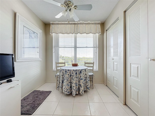 tiled dining area with ceiling fan and a textured ceiling