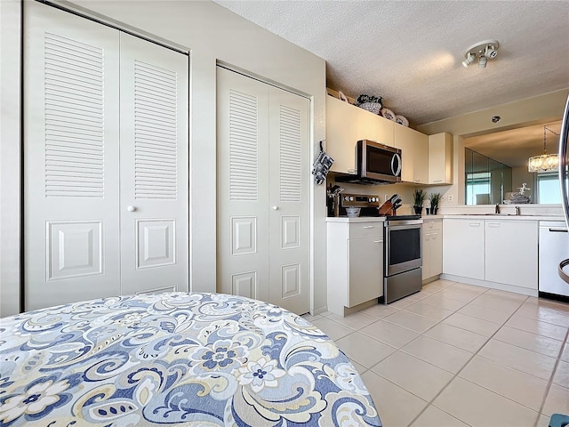 tiled bedroom with a chandelier, sink, a textured ceiling, and two closets