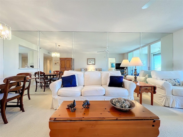 carpeted living room with ceiling fan with notable chandelier