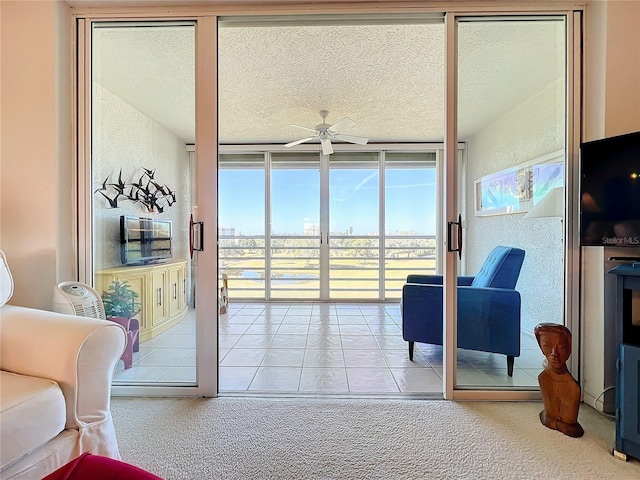 interior space with a wall of windows, light carpet, ceiling fan, and a textured ceiling