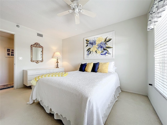 bedroom with a textured ceiling, ceiling fan, and light carpet