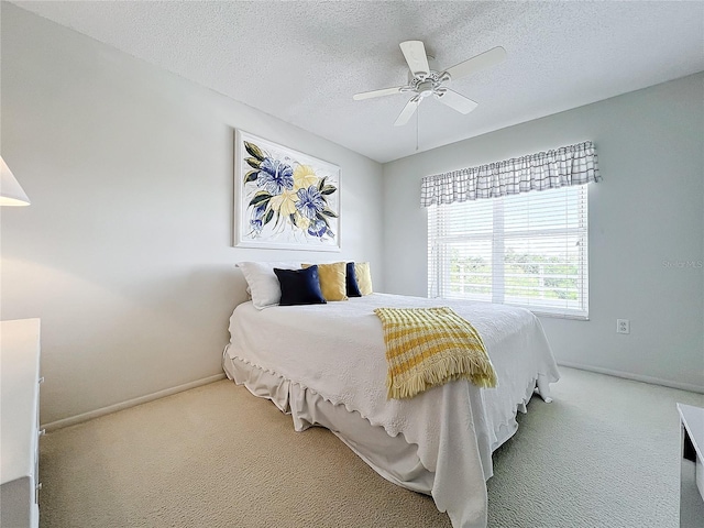 carpeted bedroom featuring ceiling fan and a textured ceiling