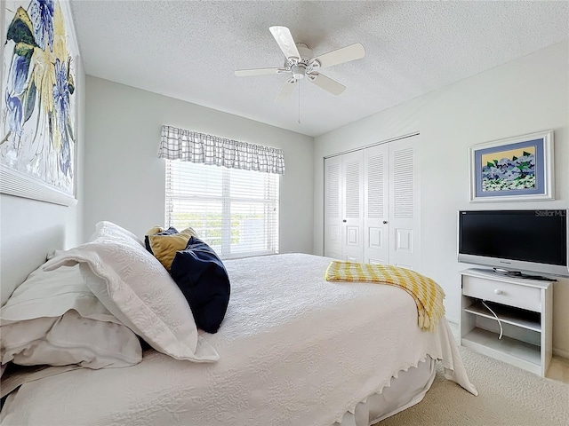 carpeted bedroom with a closet, a textured ceiling, and ceiling fan