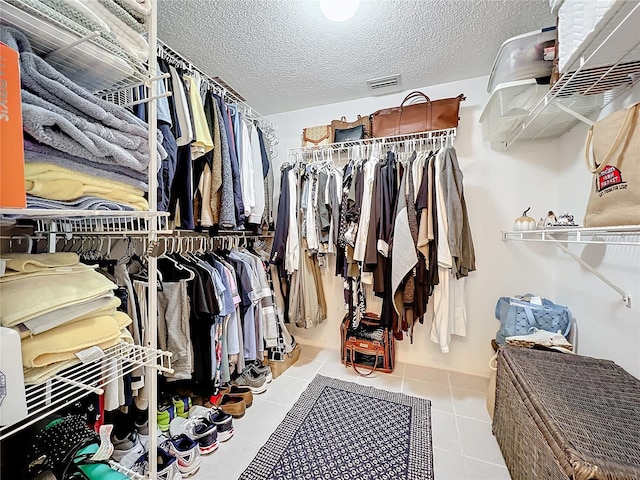 walk in closet with light tile floors