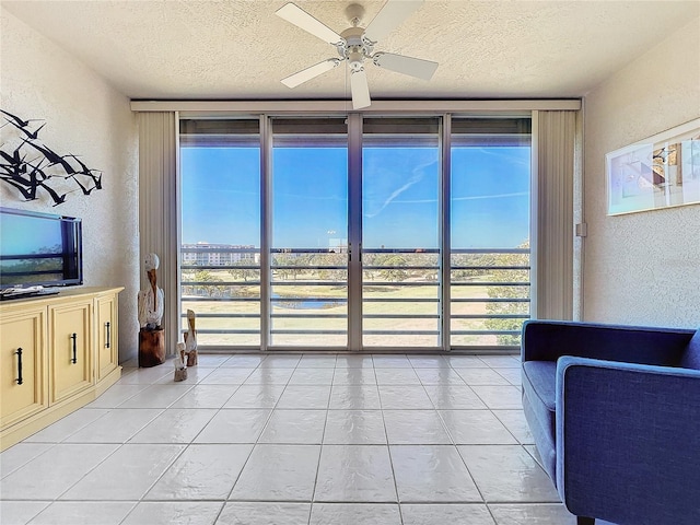 living room featuring a textured ceiling, ceiling fan, and light tile floors