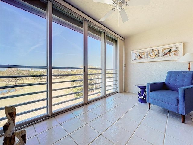 living area with ceiling fan, light tile floors, and a textured ceiling