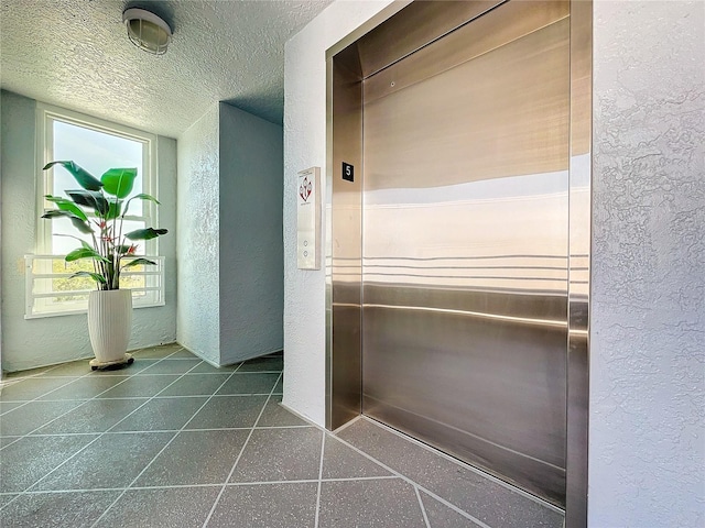 interior space with tile floors, elevator, and a textured ceiling