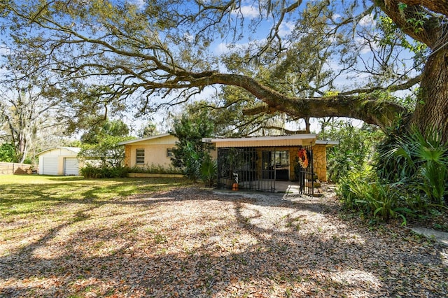 rear view of property with a lawn and a storage unit