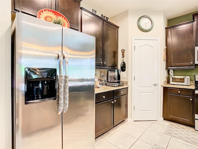 kitchen featuring dark brown cabinets, light tile flooring, stainless steel fridge with ice dispenser, and light stone counters