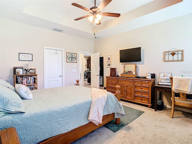 carpeted bedroom featuring a closet, ceiling fan, and a tray ceiling