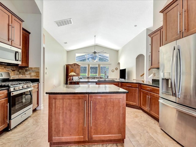 kitchen with light tile flooring, appliances with stainless steel finishes, sink, dark stone countertops, and lofted ceiling