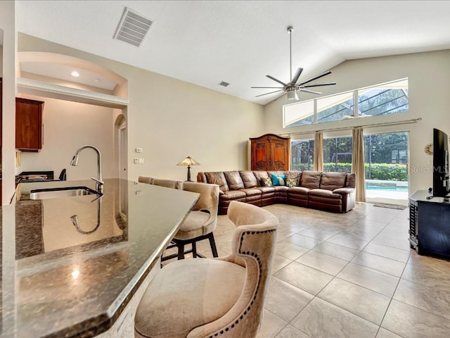 living room featuring sink, ceiling fan, light tile flooring, and lofted ceiling