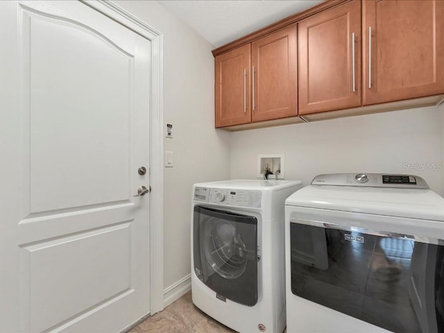 washroom featuring cabinets, hookup for a washing machine, light tile floors, and washer and clothes dryer