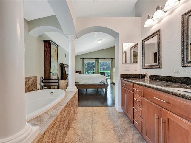 bathroom featuring vaulted ceiling, double vanity, tile flooring, decorative columns, and tiled bath