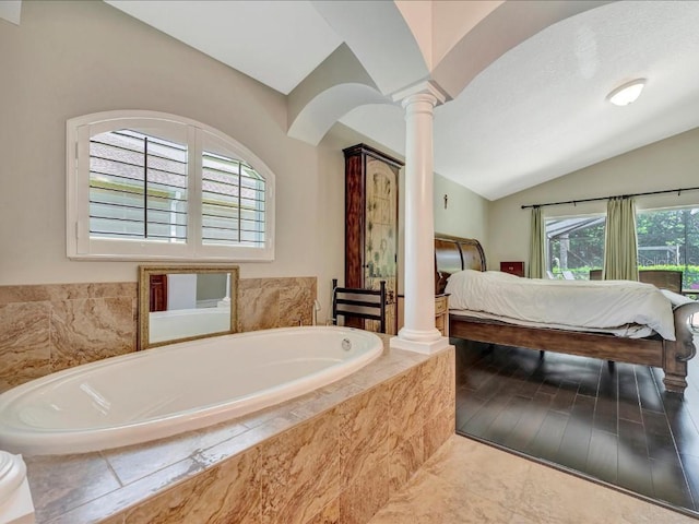 bathroom featuring vaulted ceiling, tiled bath, decorative columns, and hardwood / wood-style floors