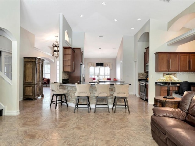 kitchen featuring kitchen peninsula, decorative light fixtures, stainless steel appliances, a kitchen breakfast bar, and light tile floors