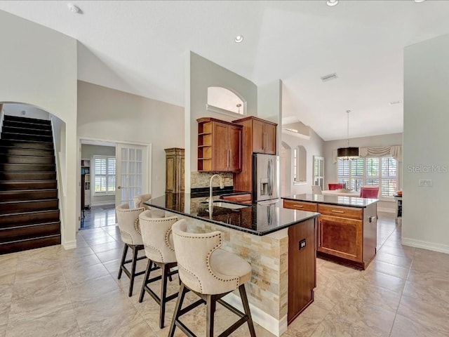 kitchen with light tile floors, sink, tasteful backsplash, decorative light fixtures, and stainless steel fridge