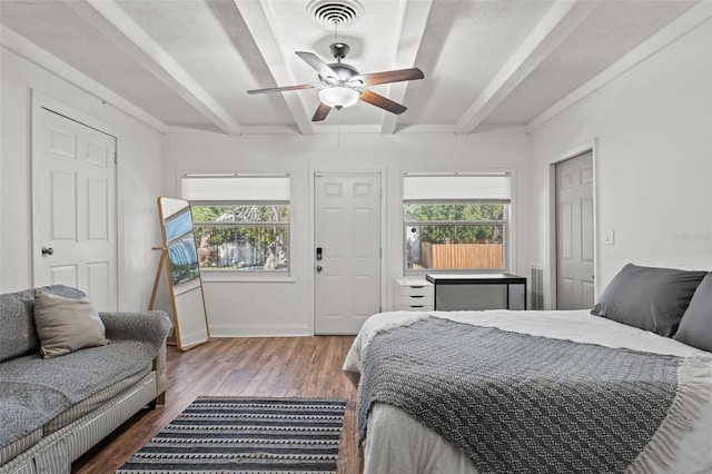 bedroom featuring multiple windows, hardwood / wood-style floors, ceiling fan, and beamed ceiling