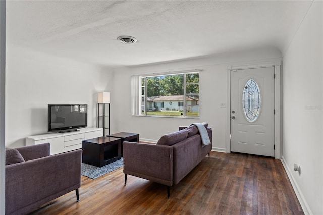 living room with a textured ceiling and dark wood-type flooring