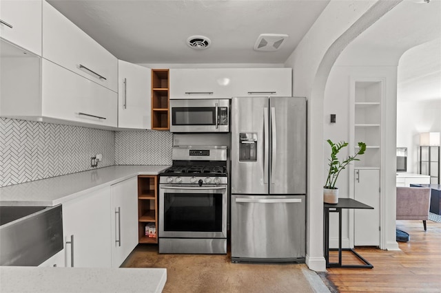 kitchen with appliances with stainless steel finishes, light wood-type flooring, decorative backsplash, and white cabinetry