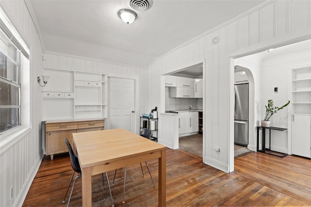 dining area with hardwood / wood-style flooring, wooden walls, and ornamental molding