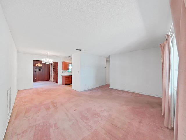 interior space featuring light carpet, a notable chandelier, and a textured ceiling