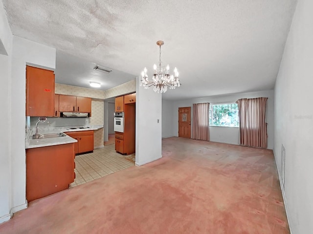 kitchen with hanging light fixtures, tasteful backsplash, sink, stainless steel oven, and an inviting chandelier