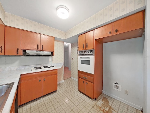 kitchen featuring tasteful backsplash, white appliances, and light tile flooring