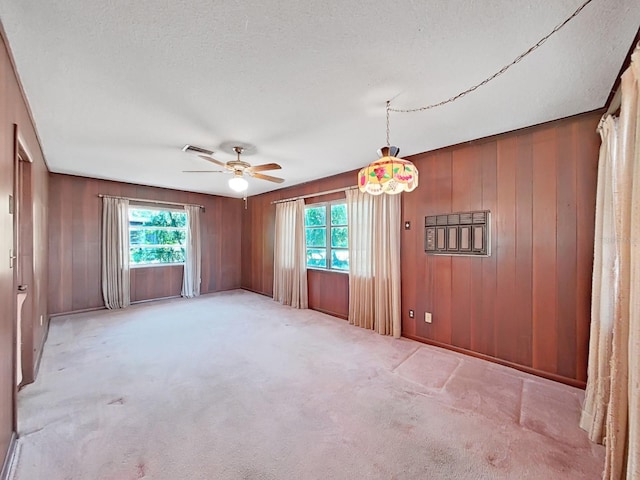 carpeted empty room with a healthy amount of sunlight, ceiling fan, and a textured ceiling