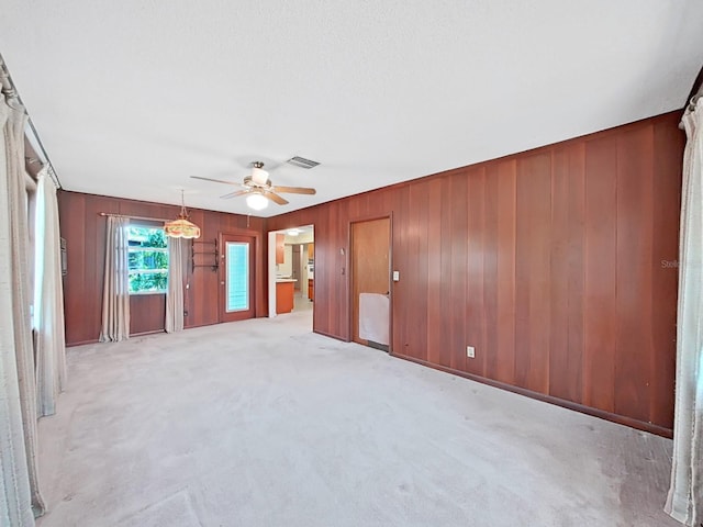 carpeted empty room with ceiling fan and wooden walls