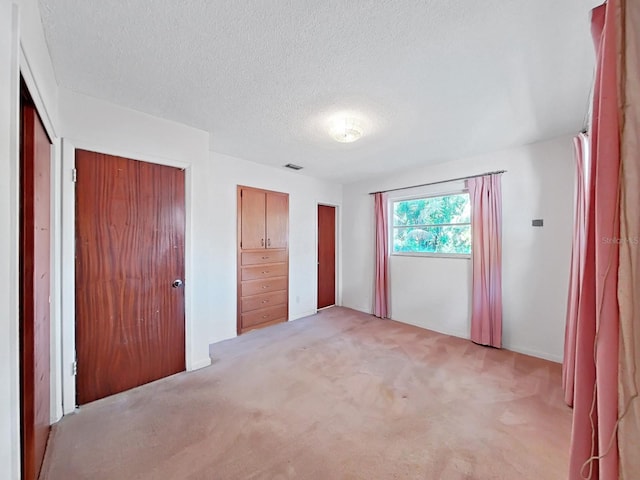 unfurnished bedroom with light carpet and a textured ceiling