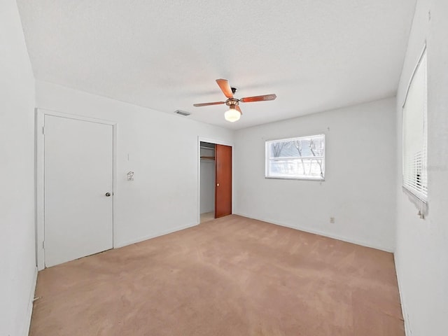 unfurnished bedroom featuring light colored carpet, a closet, and ceiling fan