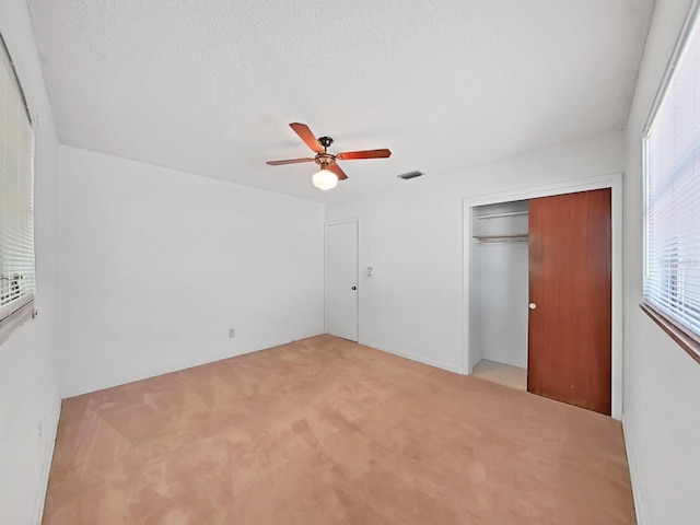 unfurnished bedroom featuring light carpet, a closet, ceiling fan, and a textured ceiling