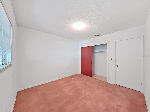 unfurnished bedroom featuring light colored carpet, a closet, and a textured ceiling