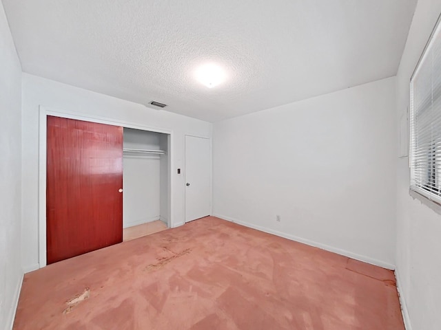 unfurnished bedroom with a closet, a textured ceiling, and light colored carpet