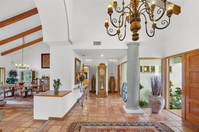 entryway featuring high vaulted ceiling, light tile patterned floors, ornate columns, and an inviting chandelier