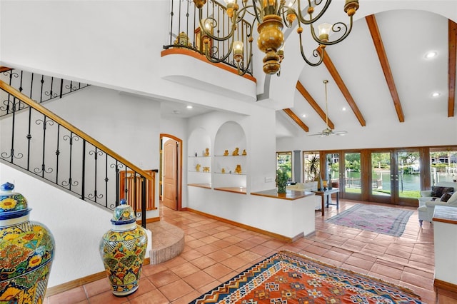 tiled entryway with beamed ceiling, ceiling fan with notable chandelier, french doors, and high vaulted ceiling