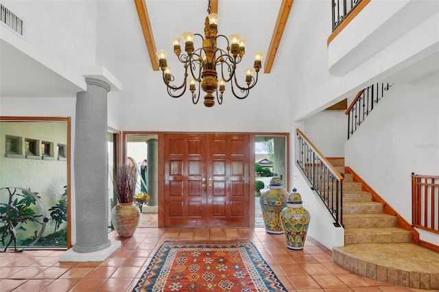 entryway with beam ceiling, a high ceiling, and decorative columns