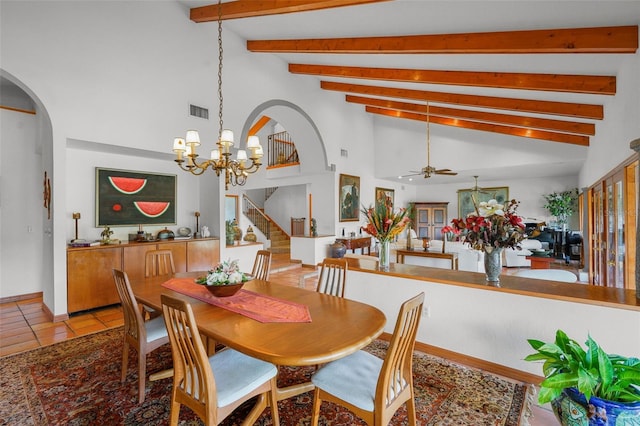 tiled dining space with ceiling fan with notable chandelier and vaulted ceiling with beams