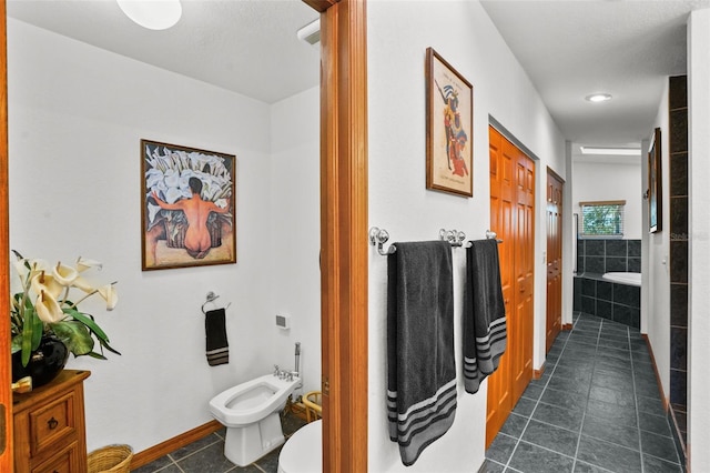 bathroom featuring a relaxing tiled tub, a bidet, and tile patterned flooring