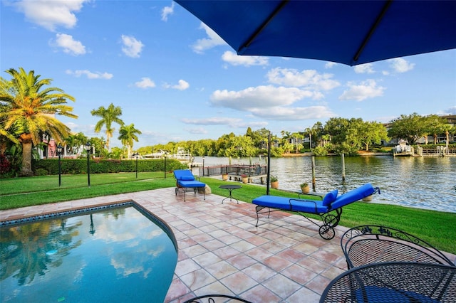 view of pool with a water view, a lawn, and a patio area