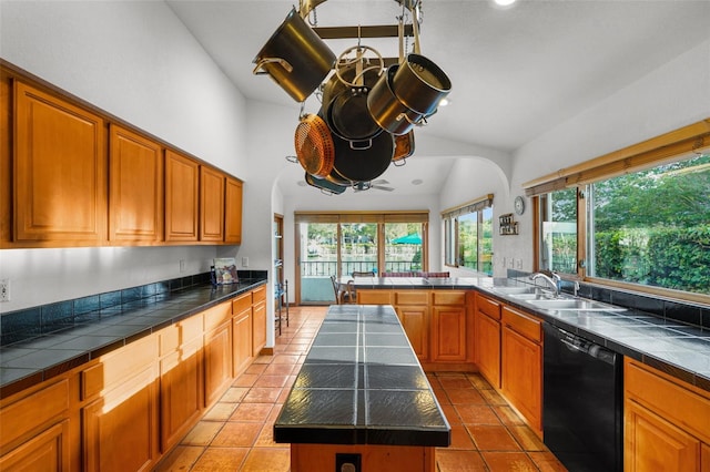 kitchen featuring a kitchen island, black dishwasher, sink, vaulted ceiling, and light tile patterned floors