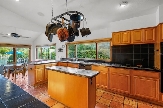 kitchen with lofted ceiling, ceiling fan, a kitchen island, black appliances, and tile counters