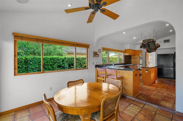 dining space featuring ceiling fan, lofted ceiling, sink, and dark tile patterned floors