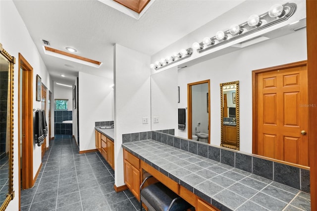 bathroom with a textured ceiling, toilet, and vanity