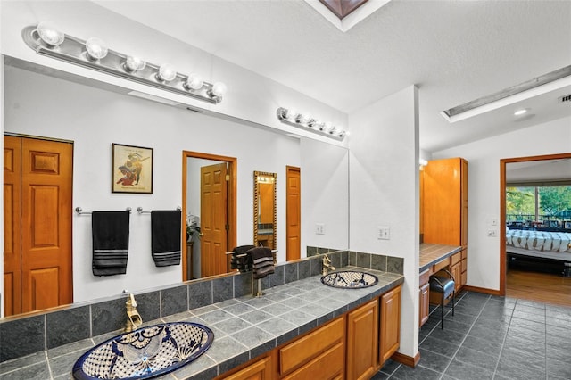 bathroom featuring a textured ceiling, vanity, and vaulted ceiling