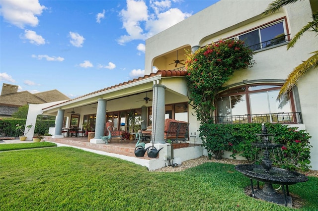 rear view of house with ceiling fan and a lawn