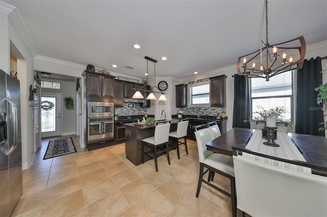 kitchen with hanging light fixtures, crown molding, backsplash, dark brown cabinets, and stainless steel appliances